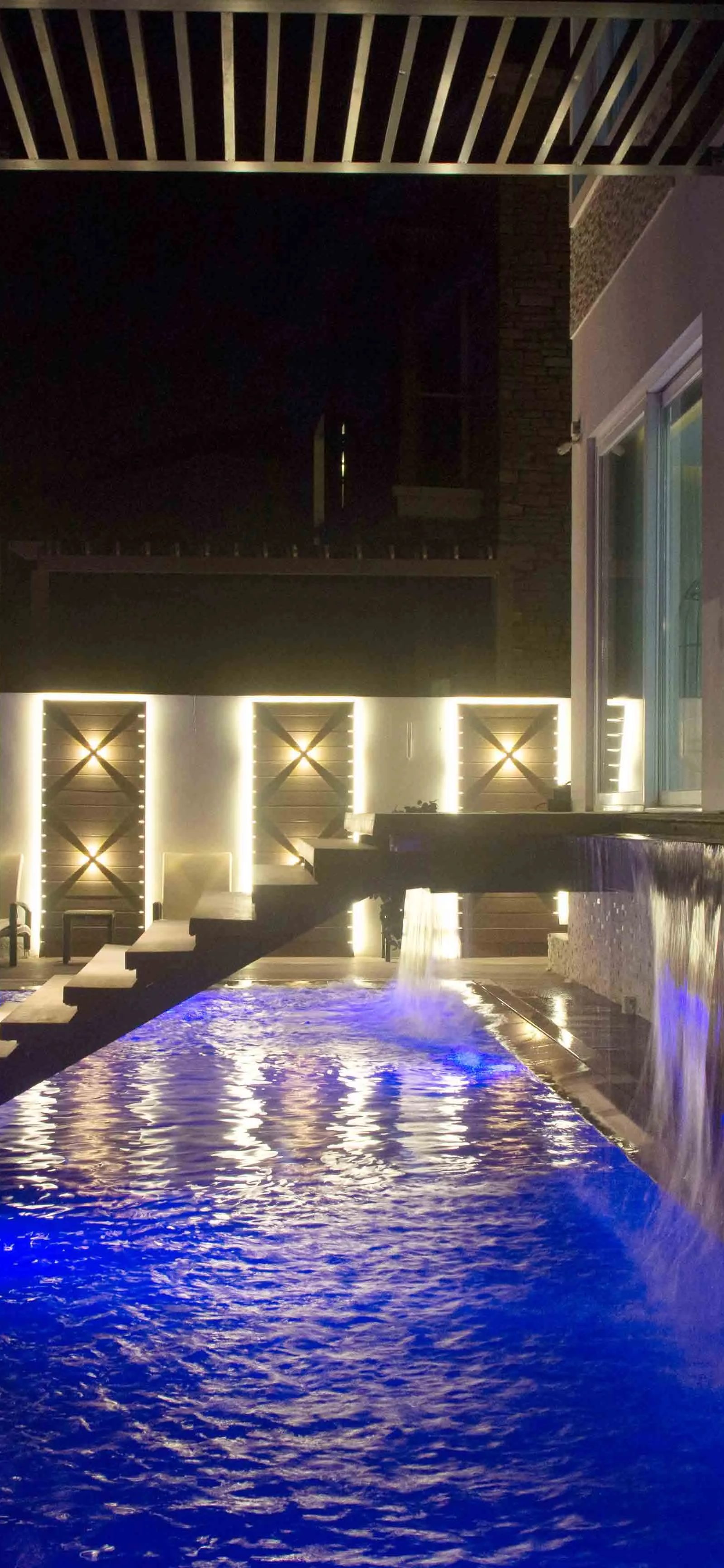 Blue pool at night by Jorge Rangel Interiors, design — industrial