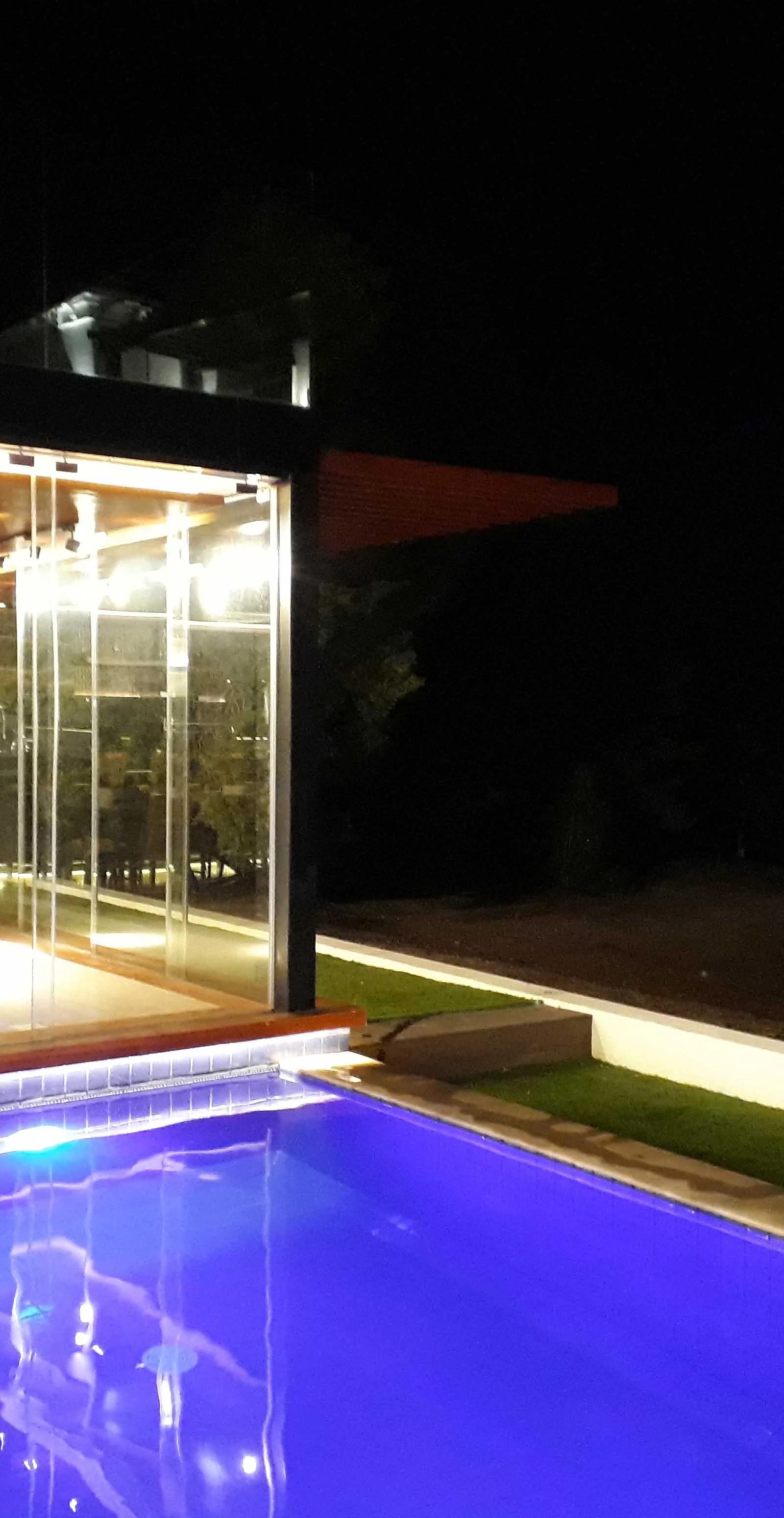 Blue pool at night by Jorge Rangel Interiors, design — industrial